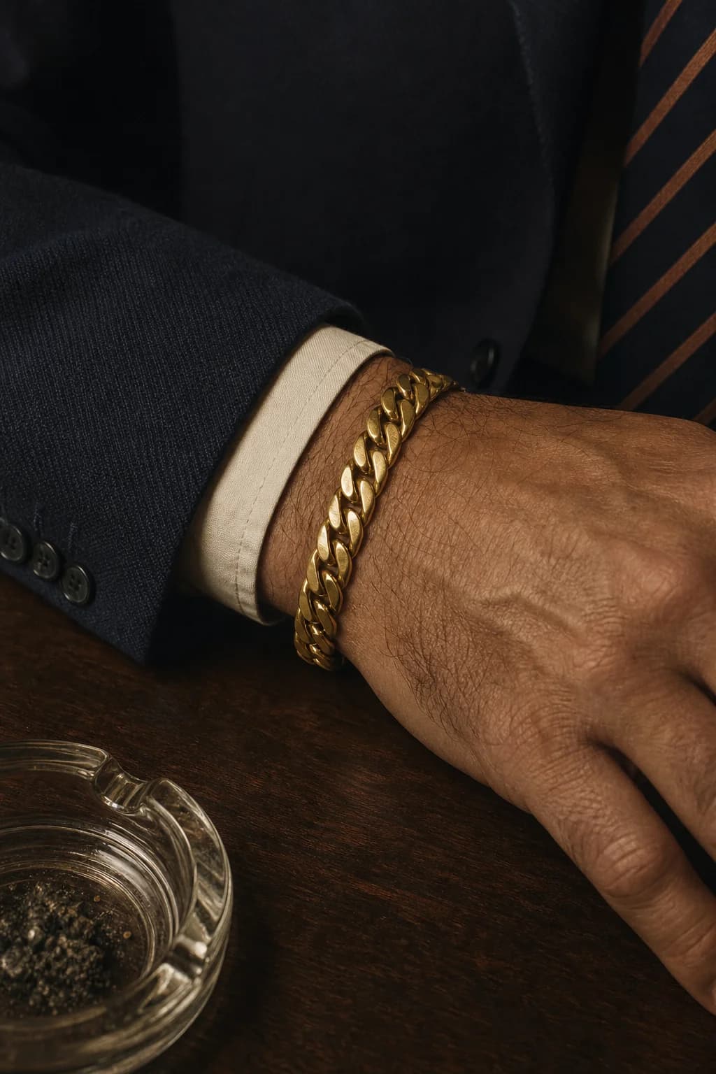 A heavy vintage gold curb bracelet worn under a navy suit cuff